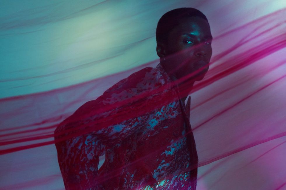 An image of the singer looking at the camera as a sheet of purple blows across him.