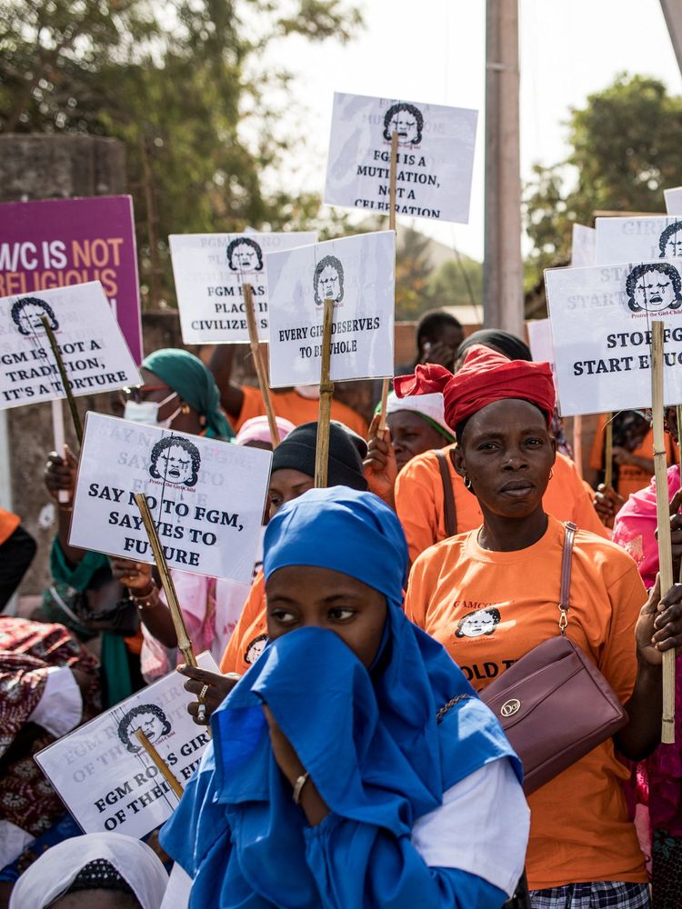 Anti Female Genital Mutilation (FGM) protesters hold placards outside the National Assembly in Banjul on march 18, 2024, during the debate between lawmakers on a highly controversial bill seeking to lift the ban on FGM.