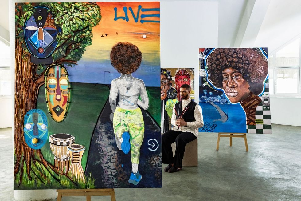 Artist Osoranna sits between two of his artworks.