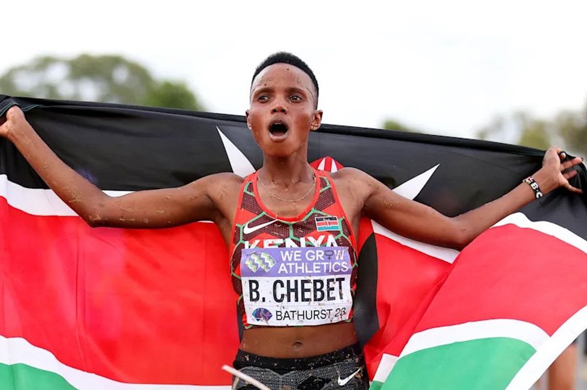 Beatrice Chebet, an African woman, holds a flag in celebration of winning a race.