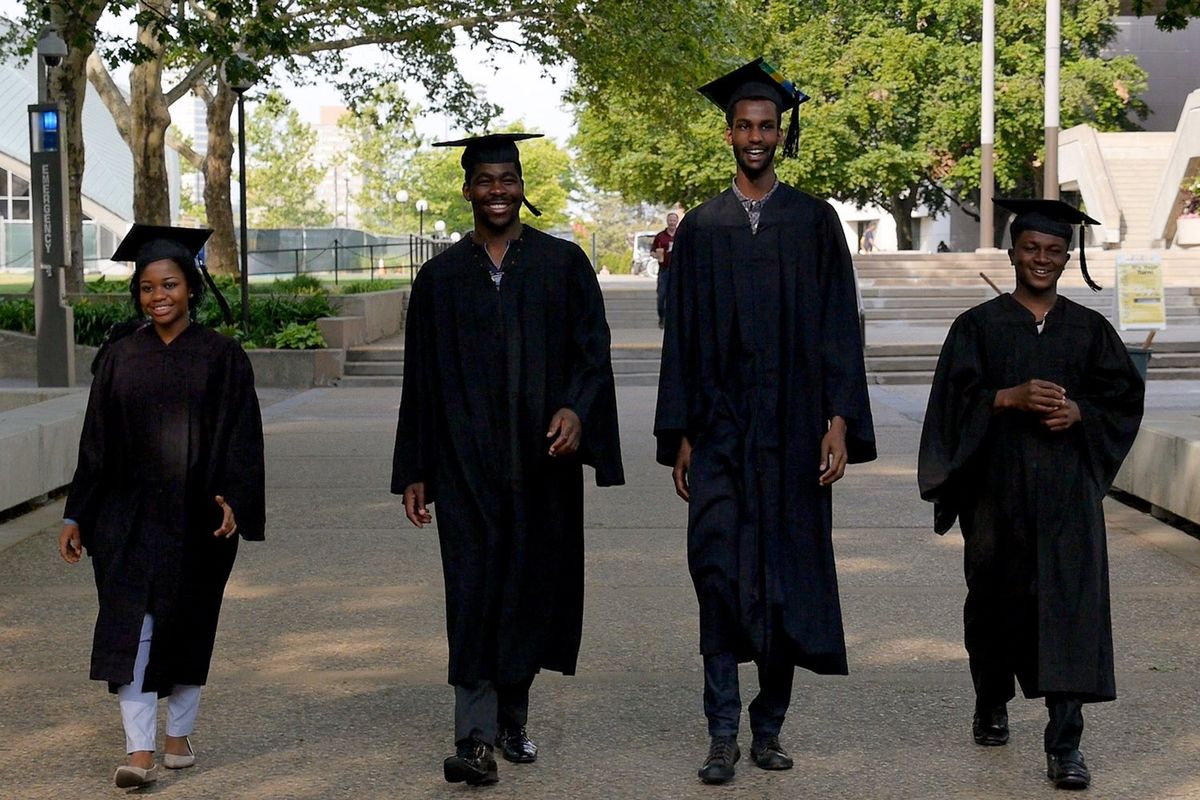 ‘Brief Tender Light’ stars Sante, Fidelis, Billy and Philip (left to right), dressed in graduation caps and gowns, walk towards the camera on the MIT campus.