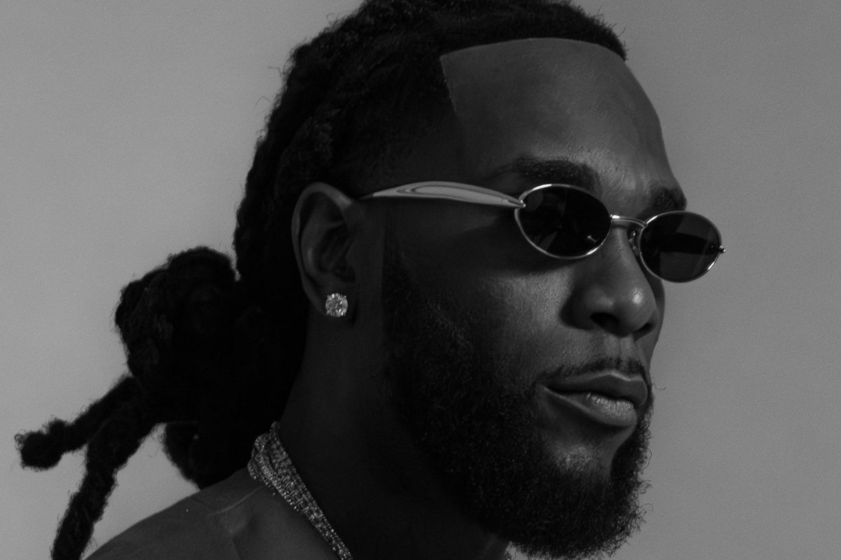 Burna Boy poses for a black and white press image wearing sunglasses.