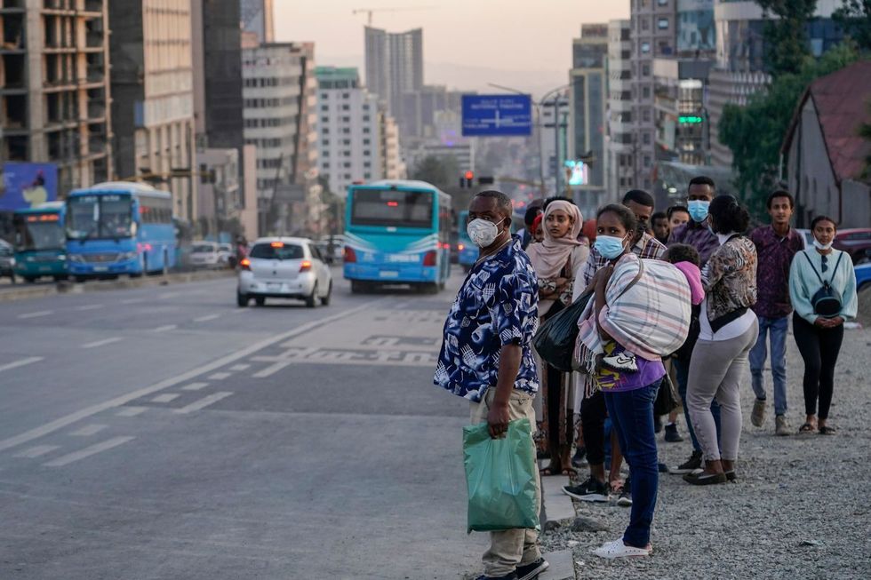 Commuters wearing masks in line with Coronavirus protocols wait in line for public transportation in Piassa during rush hour on December 25, 202, in Addis Ababa, Ethiopia.