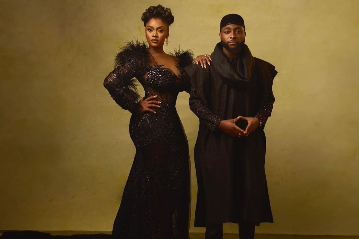 Davido and Chiamo look directly at the camera, Chioma has on a sparkling black gown with a feather detail on the shoulders and a long train.