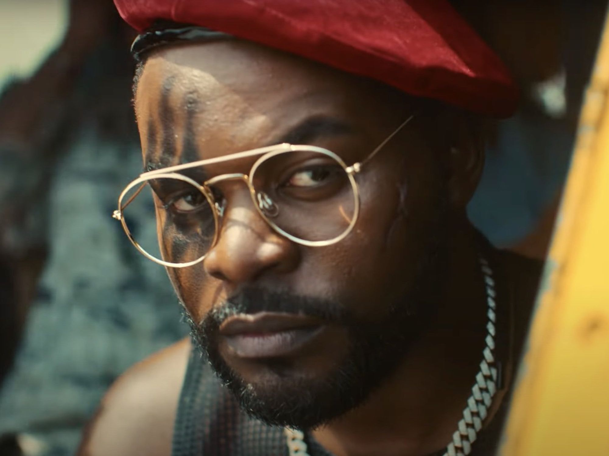 Falz wearing glasses and a red hat