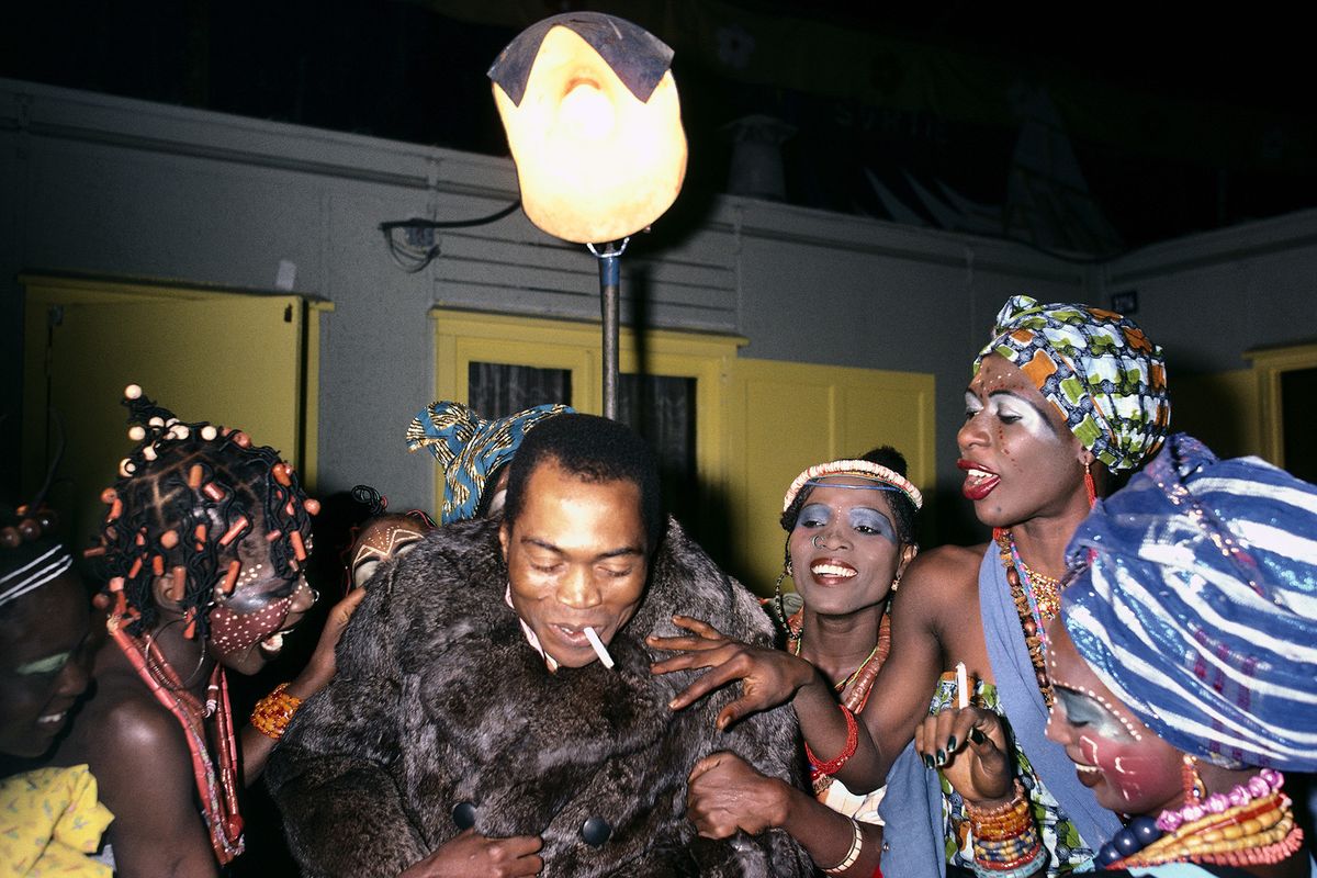 Fela Kuti in fur jacket surrounded by the Kalakuta Queens in African headwraps, facepainting and braids.