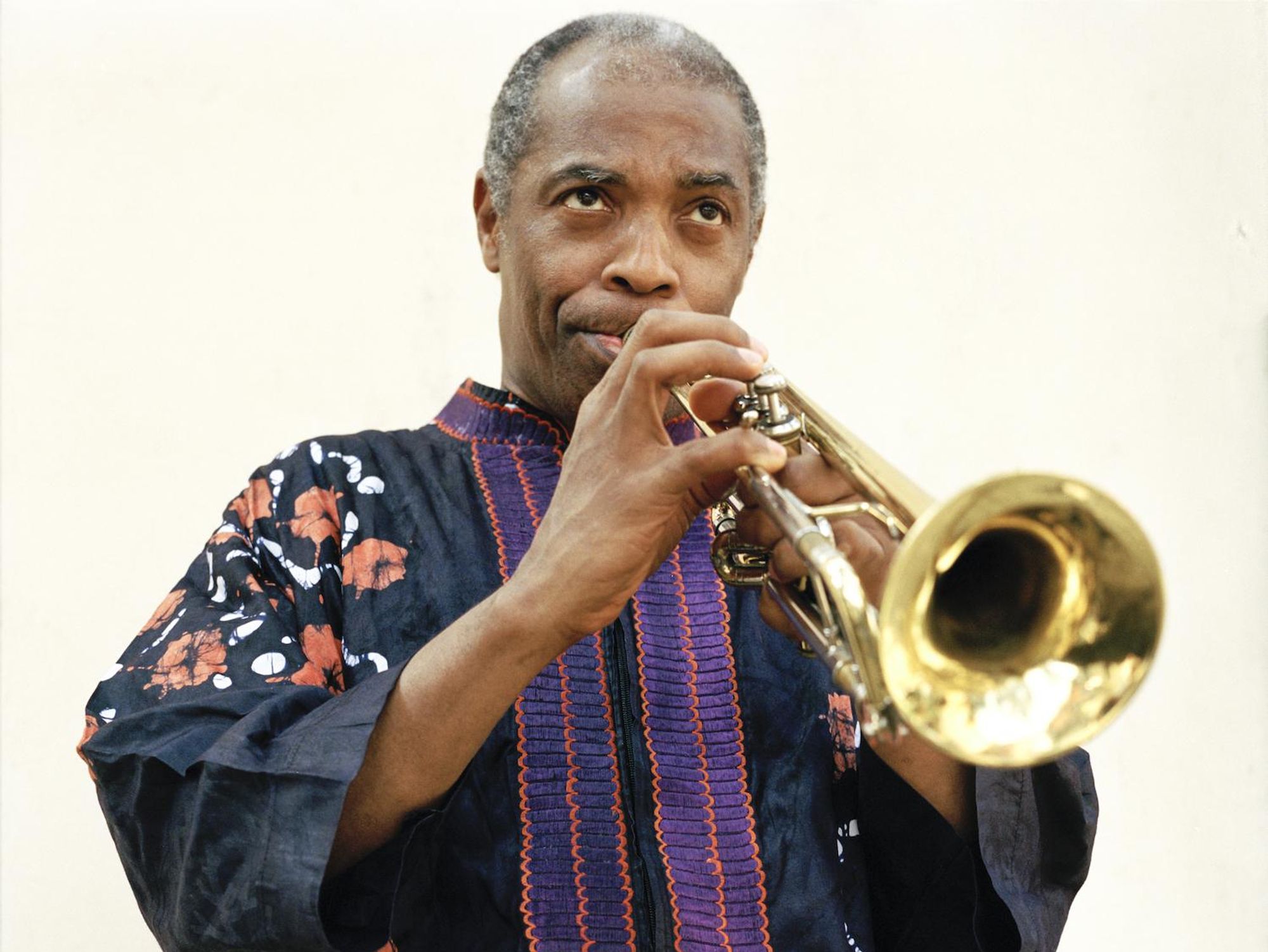 Femi Kuti stands while played a trumpet.