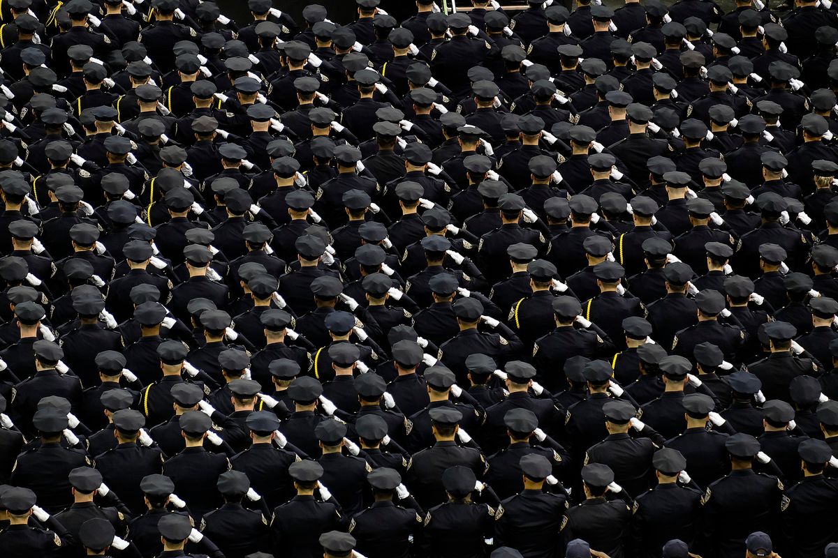 Hundreds of police stand in formation wearing ceremonial uniforms.