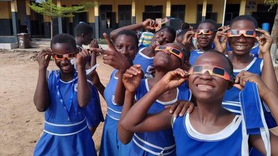 A group of children look up at the sky through 3D glasses