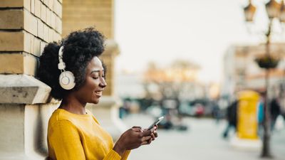 An image of a woman with headphones on and holding a cellphone.