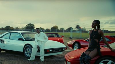 In a still from the new Wizkid music video, old cars and flashy clothes. 