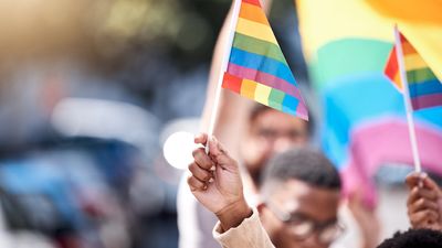 Black man holding LGBTQ+ flag