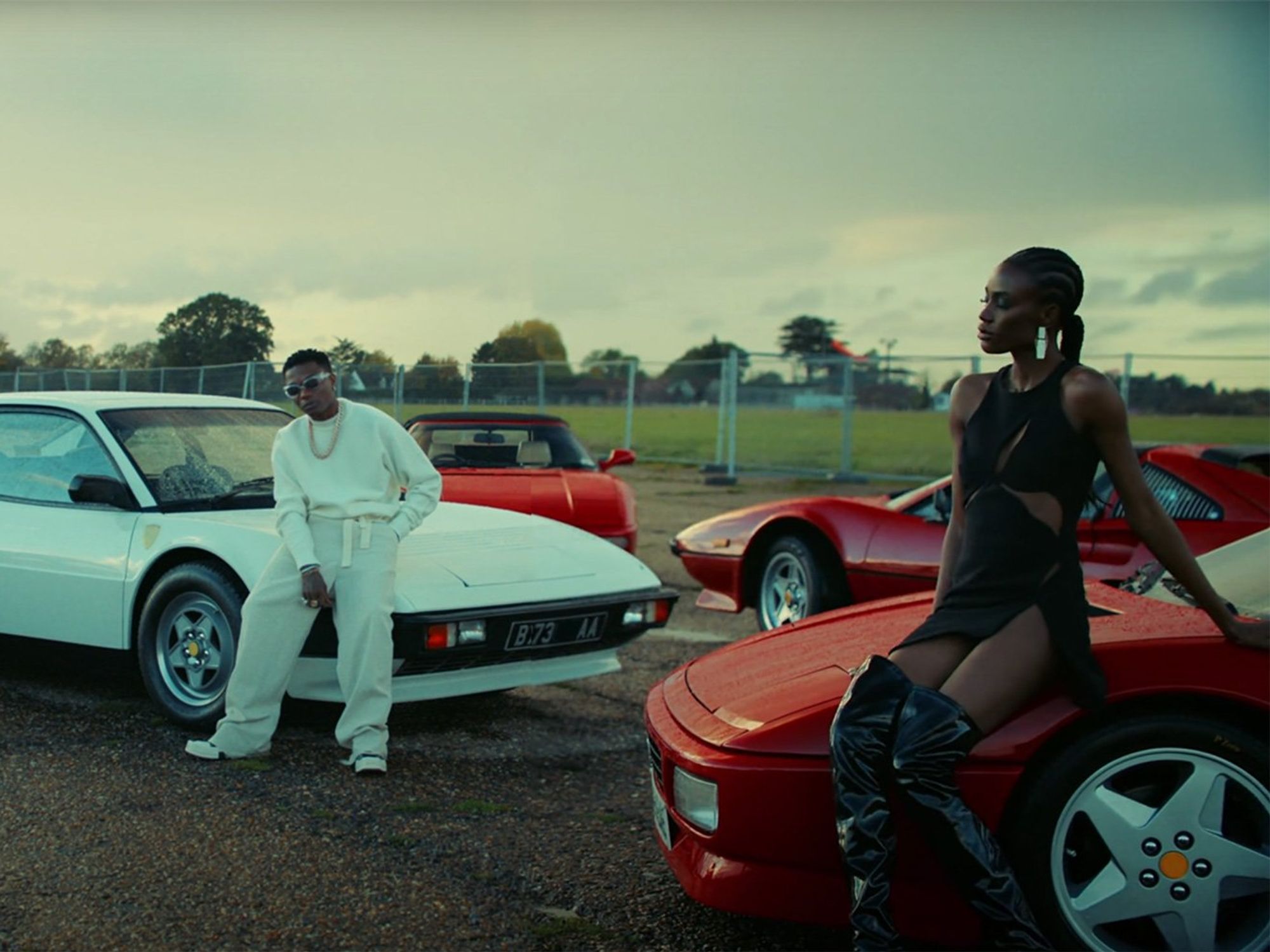 In a still from the new Wizkid music video, old cars and flashy clothes. 