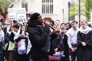 ​Kojo Acheampong, co-founder of the African and African American Resistance Organization, holds a mic to his mouth during a rally outside of Johnston Gate.