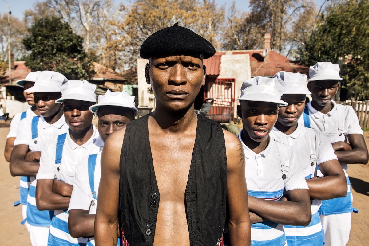 Lead actor Warren Masemola standing posing with a group of dancers on the set of Tjovitjo.