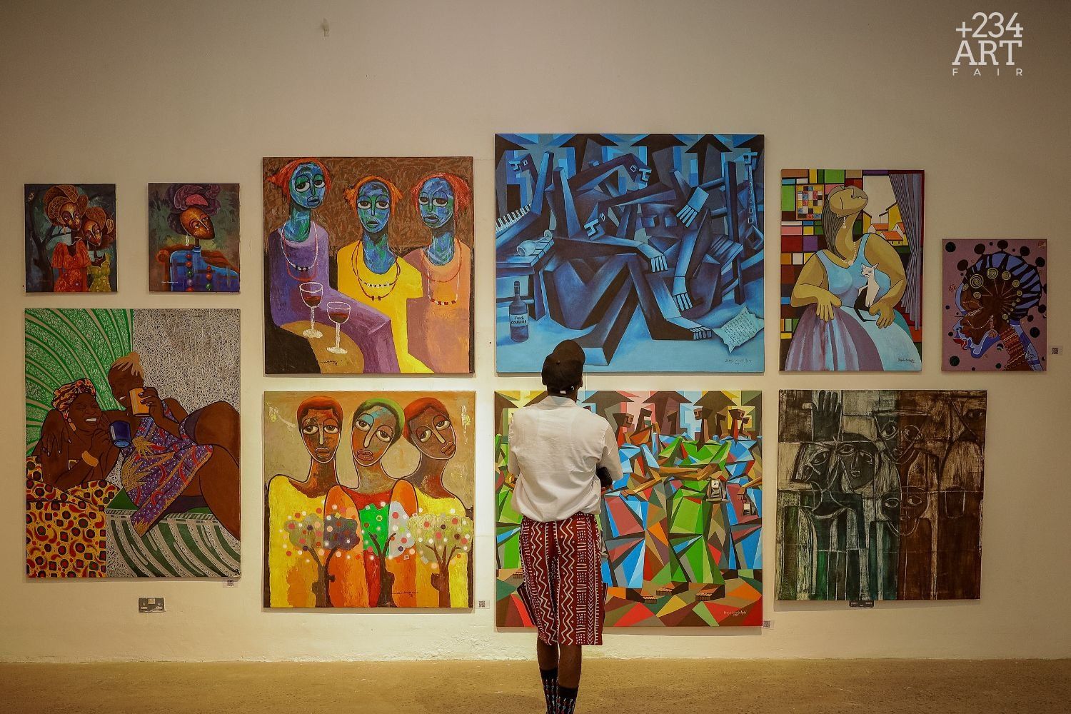A man stands in front of a wall lined with different artworks.