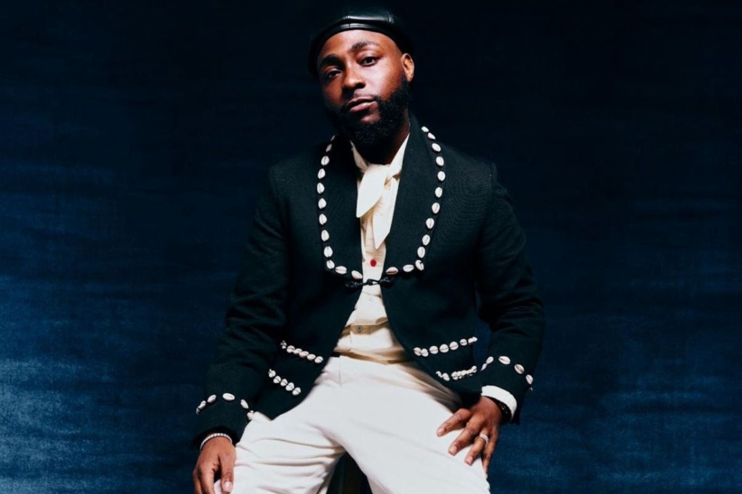 Davido poses in a navy blue and white suit in a new promotional image for his album 5ive.