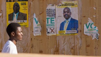 A man passes by a wall displaying campaign posters of President Emmerson Mnangagwa and his rival Nelson Chamisa during Zimbabwe's 2023 general election voter education campaign by a local civil society organisation in Harare, Zimbabwe. 