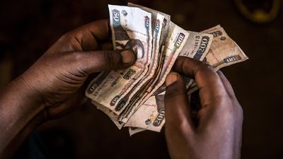 A market trader counts Kenyan shilling banknotes
