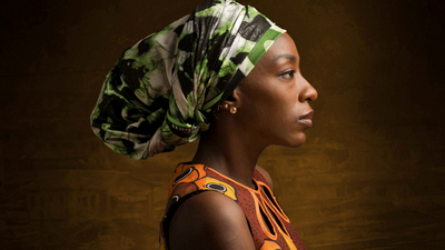 An image of a woman wearing a green wrapped headdress, side profile