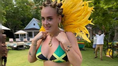 Adele in Jamaican bikini, yellow feathers and Bantu knot hairstyle.