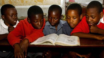 An image of five Zimbabwean pupils at a primary school reading from the same book.