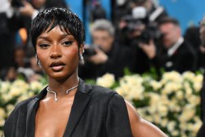 Ayra Starr in a short, cropped pixie haircut, a black outfit and a silver necklace