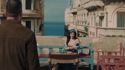Screengrab from Ramadan TV series Beit El Rifai showing a man approaching a woman sitting at a table outside on a balcony.
