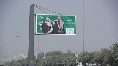 Saudi Arabian street scene with trucks and billboard of Mohammed bin Salman and father.