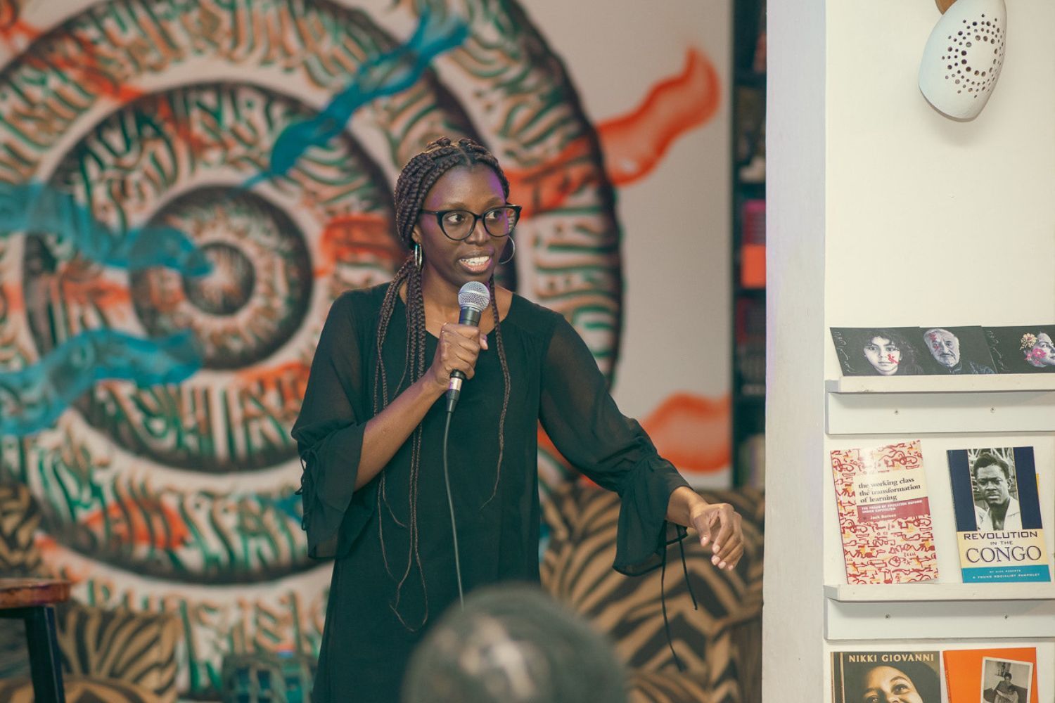 Justine Wanda holding a microphone and performing stand-up comedy 