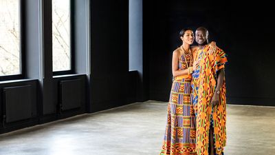 An image of a couple standing in a room wearing traditional Ghanaian outfits.