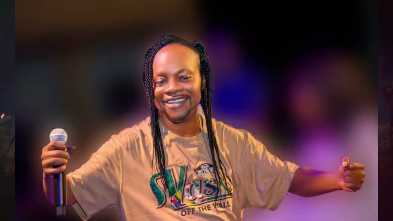 A photo of Ghanaian music legend Daddy Lumb wearing a brown t-shirt and holding a microphone.