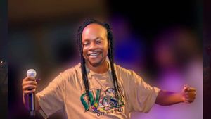 A photo of Ghanaian music legend Daddy Lumb wearing a brown t-shirt and holding a microphone.