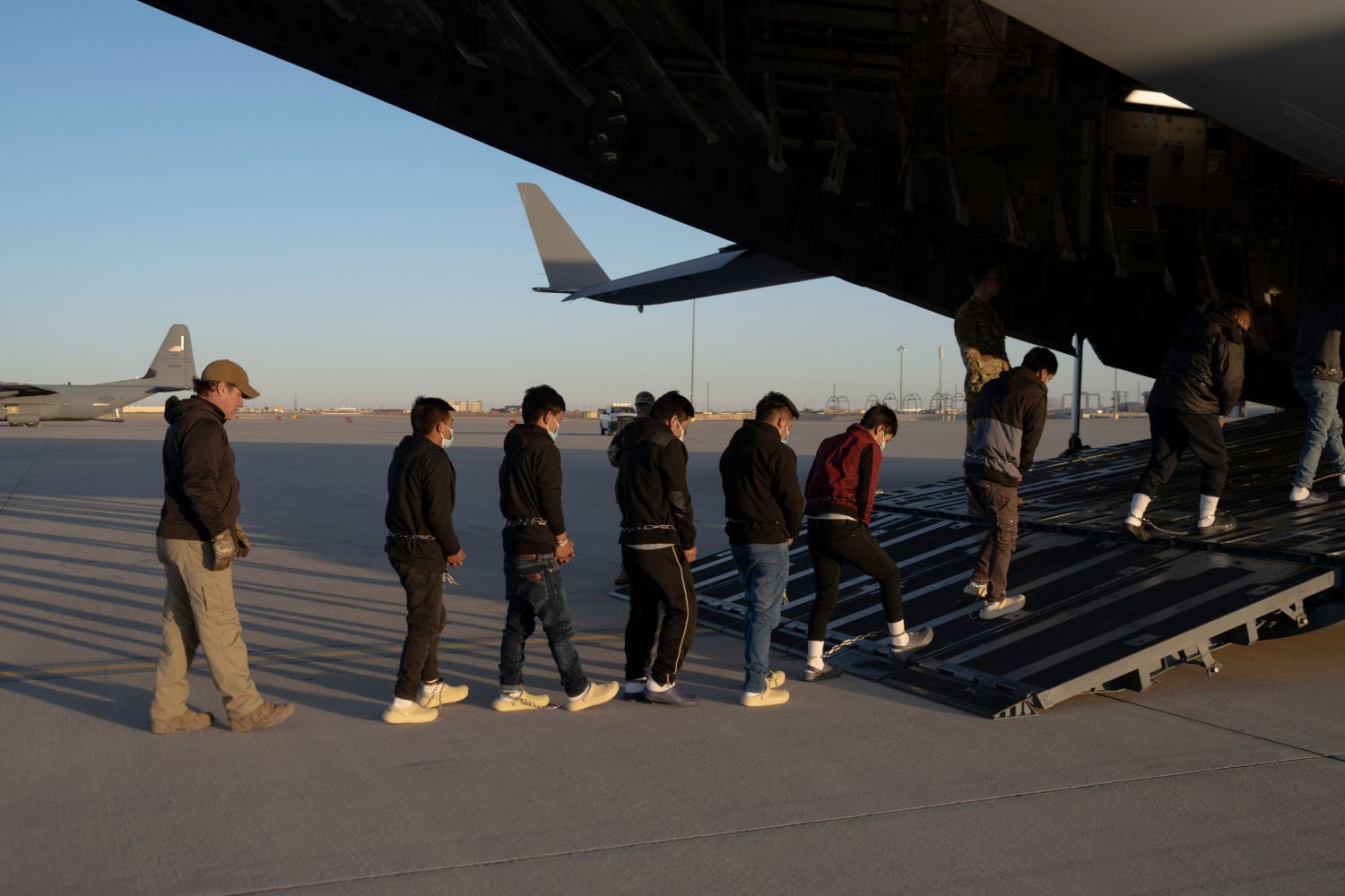 U.S. Customs and Border Protection security agents guide illegal immigrants onboard a plane