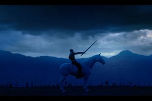 A lone person on a white horse raises a sword against a dramatic, stormy sky, set against a silhouette of mountains and distant flags