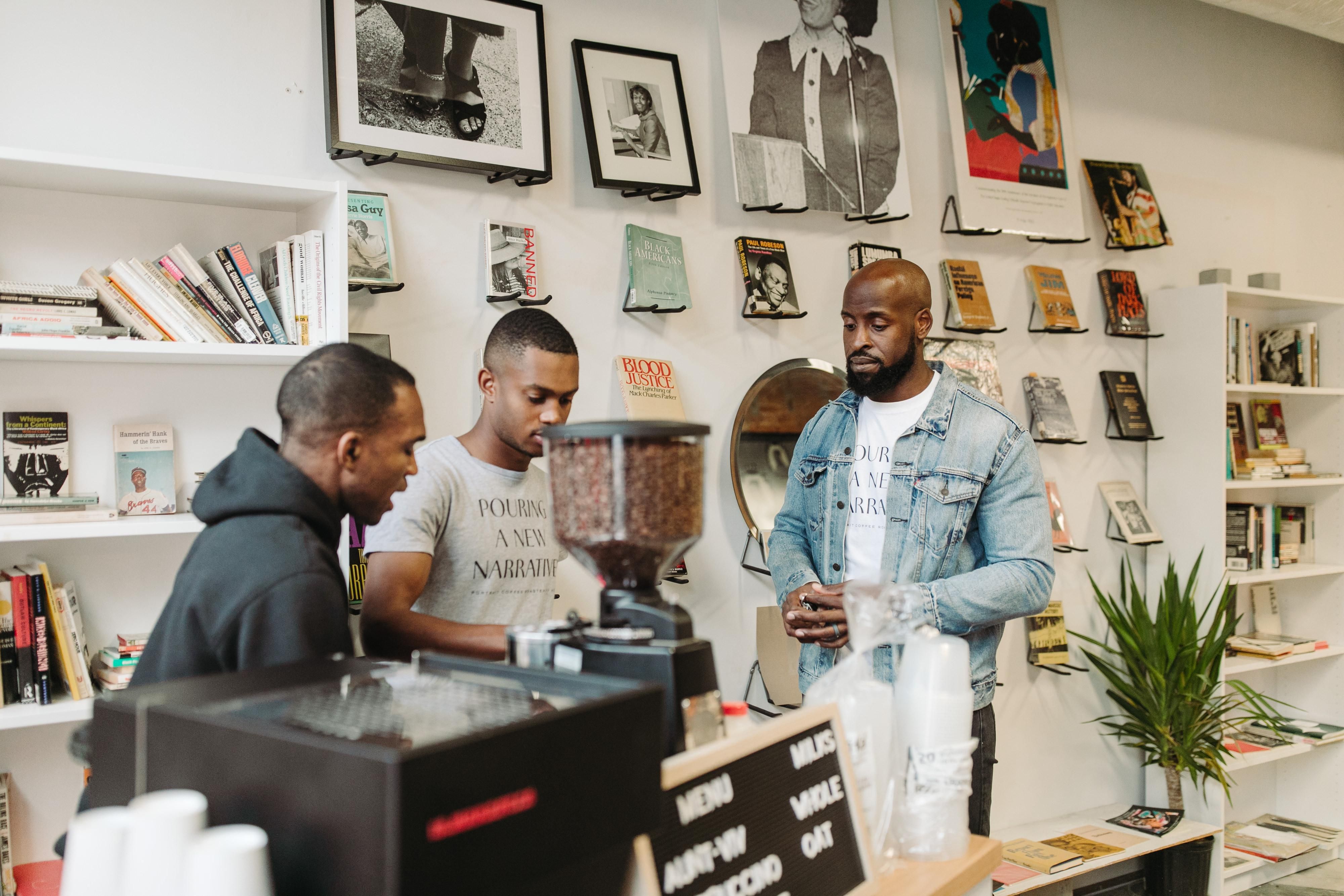 An image of three people inside a shop standing around a coffee machine.