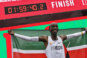 A photo of Kenya's Eliud Kipchoge celebrating with the Kenyan flag after busting the mythical two-hour barrier for the marathon.