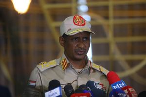 Mohamed Hamdan Dagalo speaks on a podium in front of microphones, he wears a military uniform. 