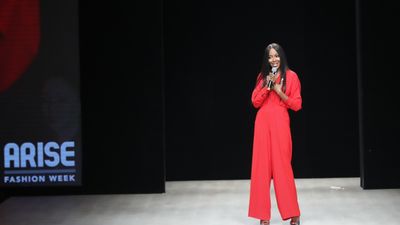 An image of Naomi Campbell with a microphone in her hand, talking to the audience at Arise Fashion Week in 2019.