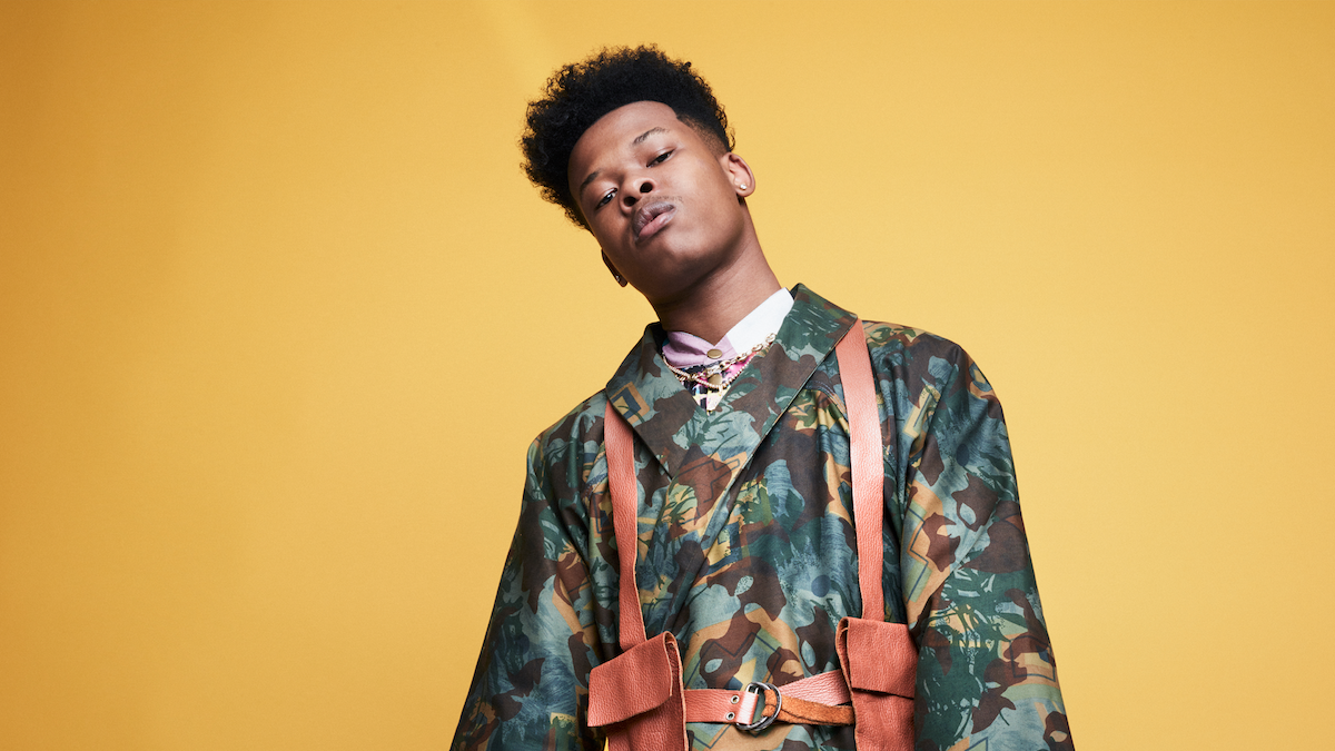 Nasty C poses in front of an amber backdrop. 