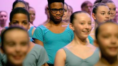 Nigerian dancer Anthony Madu, who won a scholarship after a video of him dancing in Lagos went viral, stands with ballet pupils as they give a performance for Britain's Camilla, Queen Consort during her visit to the Elmhurst Ballet School to celebrate the school's centenary, in Birmingham, on March 14, 2023.
