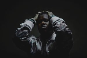 Nasty C poses for the camera with both hands on his head. 
