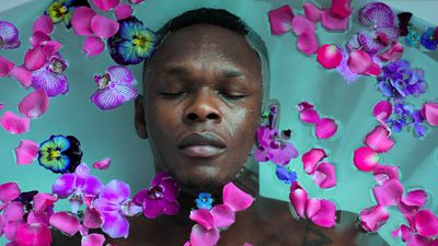 An image of Israel Adesanya floating in a pool of flowers. 