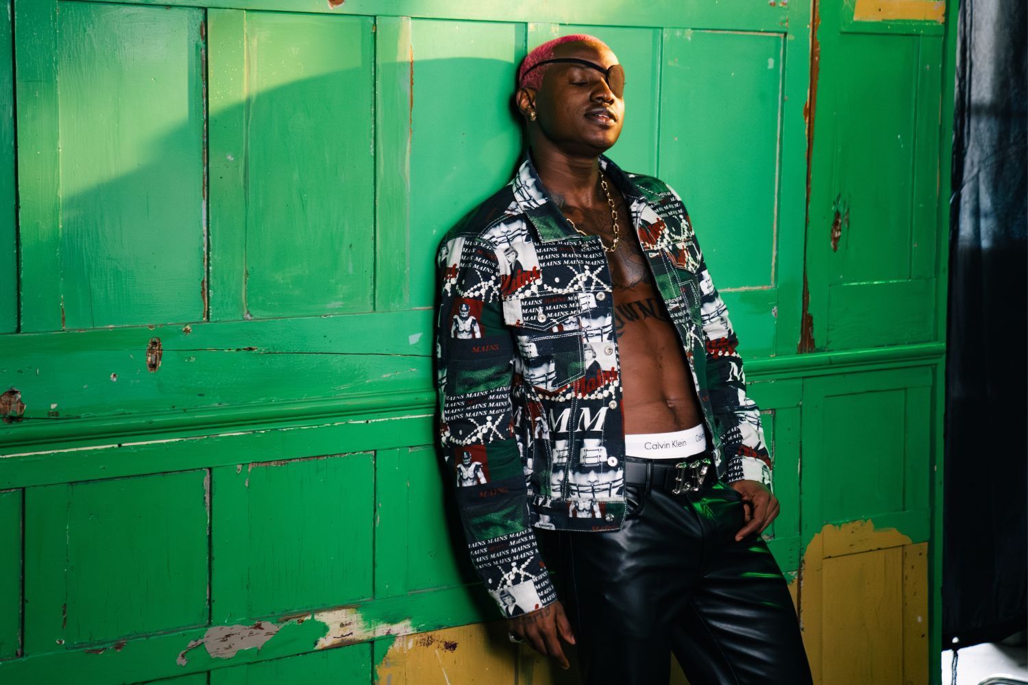Ruger poses in a colorful jacket against a green background 