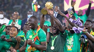 An image of Senegal captain Kalidou Koulibaly holding the AFCON trophy as his team celebrate winning the tournament in 2022.