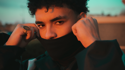 A portrait of Shane Eagle hiding his mouth with a black polo neck. 