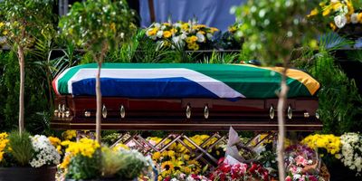 A coffin wrapped in a South African flag.