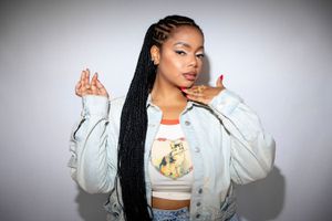 South African artist Shekhinah poses in a promotional image wearing a denim jacket. 