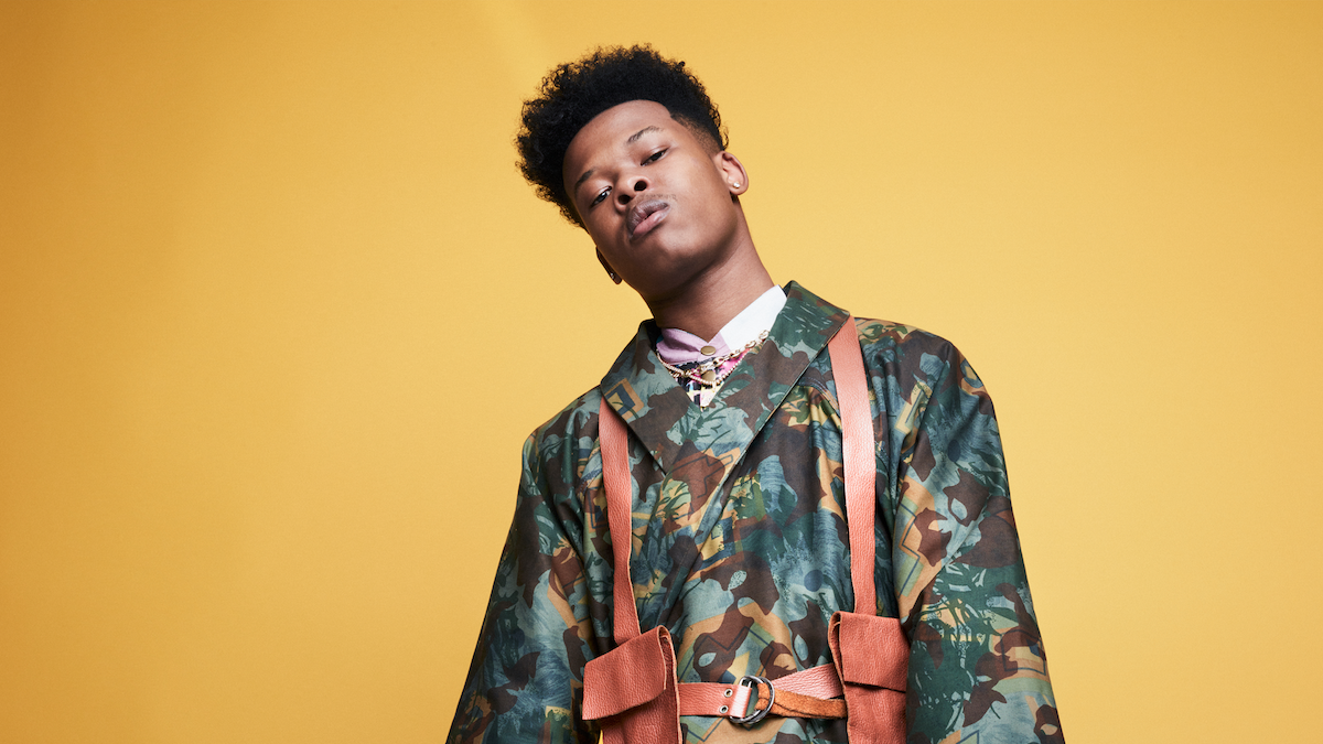 Nasty C poses in front of amber backdrop. 