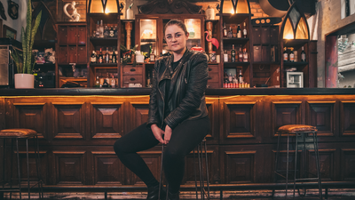 Woman wearing all black sitting on a bar stool. 